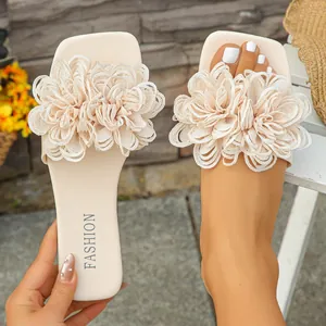 Detailed view of women's flat sandals featuring large cream fabric flowers on foot