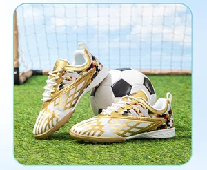 High-quality children's TF soccer shoes in gold and white on an artificial grass field