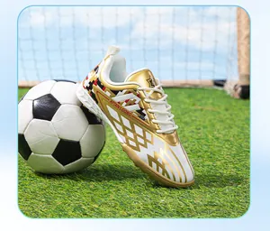 Detailed view of children's gold and white turf soccer shoe on artificial grass