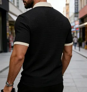 Back view of men's black waffle knit polo shirt with contrast cream collar and cuffs