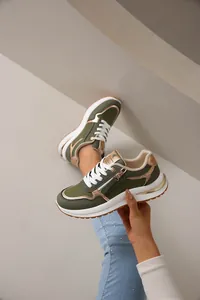 Detalle de zapatilla deportiva verde oliva para mujer con detalles dorados y cremallera