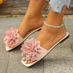 Close-up of stylish beige flat sandals featuring large pink floral lace designs