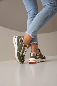 Primer plano de zapatillas de moda para mujer en verde y dorado con cremallera lateral
