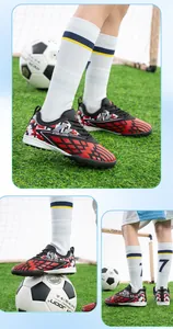 Detail view of red and black kids turf soccer shoes for training on synthetic grass