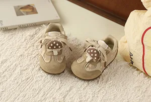 Detailed macro view of toddler girls' beige floral sneakers with mushroom charm.