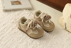 Close-up view of stylish girls' floral sneakers with mushroom charm on a white rug