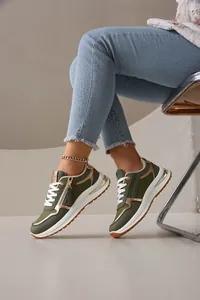 Primer plano de zapatillas de moda verde oliva y dorado con vaqueros azules con tachuelas.
