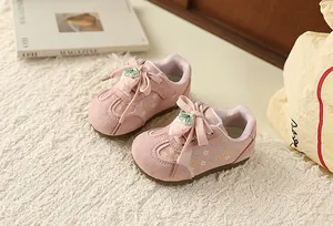 Detailed macro view of pink floral toddler sneakers featuring a cute strawberry lace decoration