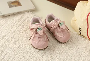 Close-up of pink toddler trainers with sweet floral print and strawberry lace charms