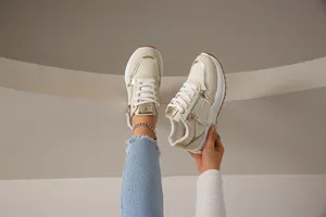 Elegantes zapatillas beige con detalles dorados y cremallera lateral