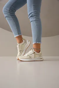 Vista detallada de elegantes zapatillas de plataforma crema y oro en un modelo