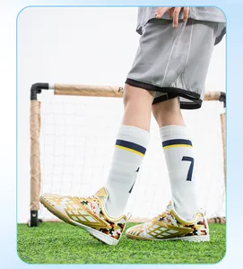 Detailed side profile of children's gold and white turf soccer shoes on green grass