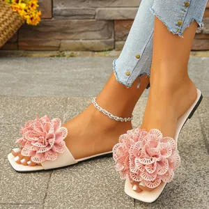 Detailed view of the large decorative pink fabric flowers on women's flat beach sandals