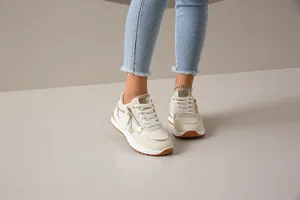Primer plano de zapatillas de moda beige con detalles dorados y cremallera elegante