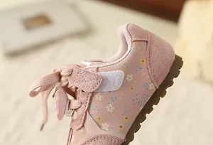 Detailed macro view showing sweet pink floral patterns and suede texture on girls sneakers