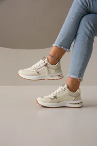 Vista lateral de zapatillas de moda crema para mujer con detalles dorados y cremallera