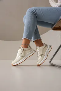 Vista detallada de zapatillas de moda beige y doradas para mujer con cremallera lateral