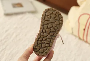 Close-up view of the non-slip brown rubber sole of a pink floral girl's sneaker