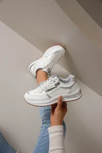 Primer plano detallado de zapatillas de moda blancas para mujer con detalles plateados y cremallera