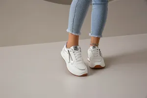 Primer plano de zapatillas blancas de moda con cremallera lateral y detalles plateados