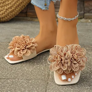 Close-up detail of stylish beige flat slippers featuring large decorative fabric flowers