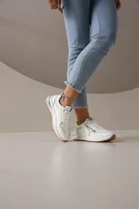 Zapatillas de moda blancas para mujer con detalles plateados y suela de goma marrón.