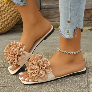 Detailed view of women's beige flat sandals with large decorative fabric flowers