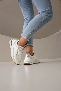 Primer plano de zapatillas de moda blancas y plateadas con cremallera lateral y suela gruesa