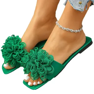 Stylish green flat slides for women featuring a large decorative woven flower detail.