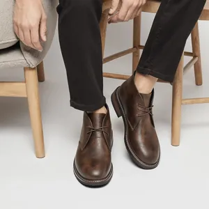 Gros plan de bottines désert classiques en cuir marron vintage portées par un mannequin