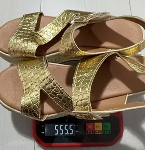 Detail view of gold metallic platform wedge sandals weighing 555.5 grams on a scale.