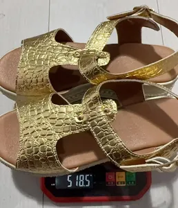 Detail view of golden crocodile textured platform sandals on scale showing 518.5g weight