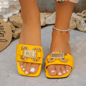 Primer plano de sandalias planas amarillas con una gran hebilla dorada decorativa