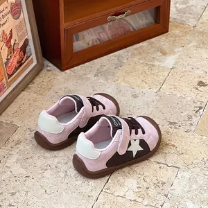 Close-up of pink and brown children's soft-sole walking shoes with star design