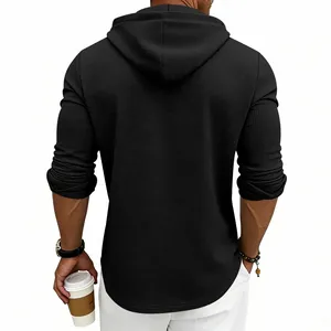 Detailed back view of a men's black waffle knit hoodie showing texture and hood design