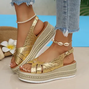 Detailed view of fashionable gold crocodile embossed platform wedge sandals on feet