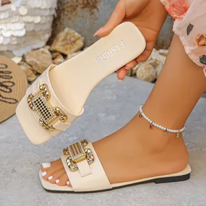 Primer plano detallado de sandalias planas beige con una elegante hebilla metálica