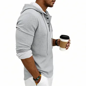 Side profile of a men's grey waffle knit long sleeve hooded Henley shirt with a coffee cup