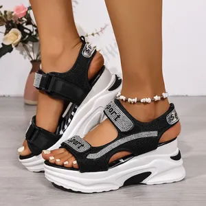 Dettaglio ravvicinato di sandali con zeppa platform bianco e nero con cinturini in strass.