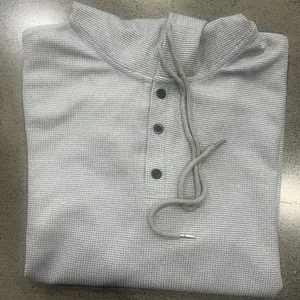 Detailed view of a gray waffle knit hoodie showing three-button Henley neck and drawstring