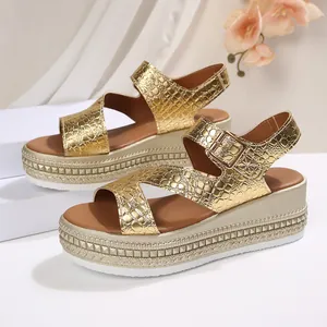 Detailed view of gold crocodile-textured platform sandals with wedge heels and buckle.