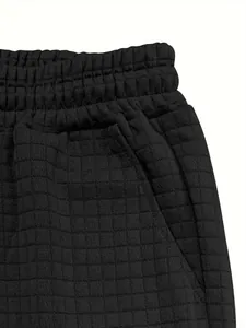 Detailed view of black waffle texture fabric and elastic waistband on men's casual shorts