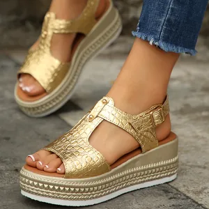 Close-up of golden platform sandals with crocodile texture on a stone background.