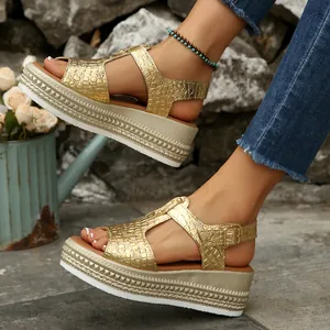 Close-up of stylish gold crocodile-pattern platform wedge sandals with buckle straps