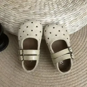 Détail de chaussures Mary Jane à pois beige pour fille avec doubles boucles sur tapis de paille