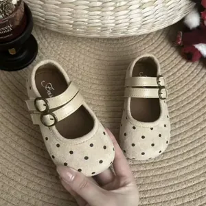 Gros plan sur des chaussures Mary Jane à pois beiges pour filles à double bride