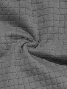 Macro view showing the breathable grey waffle grid fabric texture of a men's polo sports set