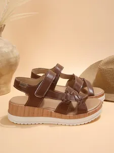 Close-up view of brown platform wedge sandals featuring a wood-grain texture and adjustable straps