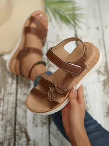 Close-up detail of stylish brown platform wedge sandals for women with white stitching