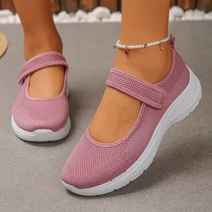 Close-up detail of pink breathable fly-knit Mary Jane flats worn by model on grey background